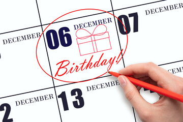 The hand circles the date on the calendar 6 December, draws a gift box and writes the text Birthday. Holiday.