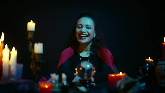 Black witch crystal-gazer laughing mysteriously and ominously, dark magic