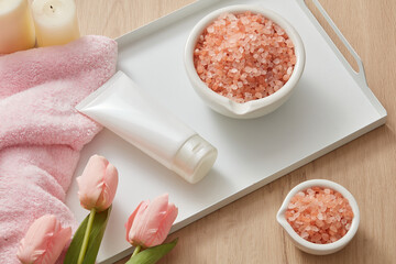 Obraz na płótnie Canvas Front view of himalaya salt decorated with tray towel and flower cosmetic jar in table background 