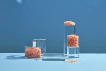 Front view of himalaya salt decorated with transparent podium in blue background abstract