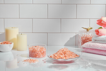 Front view of spa using himalaya salt in dish decorated with candles and tower flower in ceramic tiles background