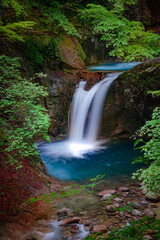 Beautiful Jungle waterfall in a tropical forest with rock and turquoise blue freshwater river. Summer season new leaves. Natural landscape background. Its name is Nishizawa Yamanashi, Japan