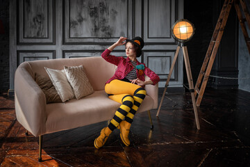 A beautiful animator or cabaret girl in a costume of a ringmaster (entertainer) of an old circus: a red striped tailcoat, a bowler hat, a striped black and yellow tights. Vintage steampunk style