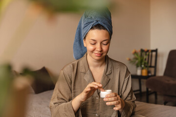 Full view of young woman sitting at home with cream