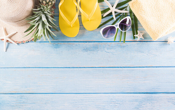 Summer holiday, travel and vacation concept. Sunglasses, starfish, beach hat, flip flop and sea shell on pastel blue wooden background.