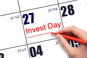 Hand drawing red line and writing the text Invest Day on calendar date June 27.  Business and...