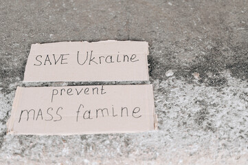 Poster Prevent mass famine. Save Ukraine poster. poster lies on concrete ground.