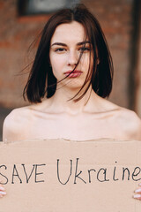 Close-up Portrait of Nude Woman with Poster Save Ukraine. woman with a belligerent look.