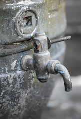 An einem alten Bierfass ist ein Ablasshan angebracht.