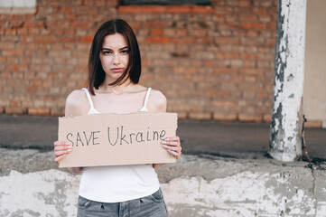 Portrait of a young brunette woman on background of a brick wall. He looks sadly at camera.