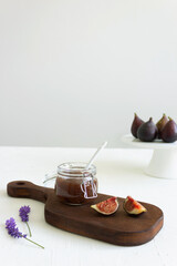 Homemade fig jam in the jar and fresh fig on the rustic wood board with on the white background