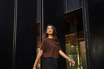 Stylish businesswoman walking on street with phone