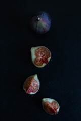 One whole and one halved figs on the black background flat lay (top view)