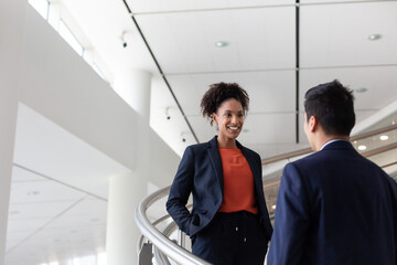 African American businesswoman talking with a colleague on a staircase in an office