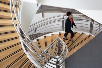 African American businesswoman walking up spiral staircase in office
