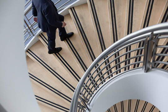 Businessman walking up spiral staircase in office