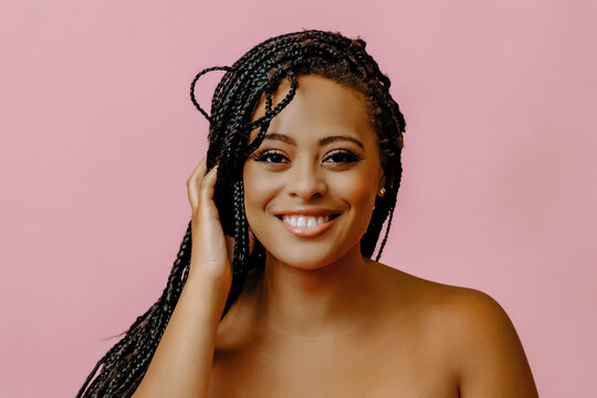 beauty headshot of smiling young adult black woman braid hair on pink background looking at camera studio shot