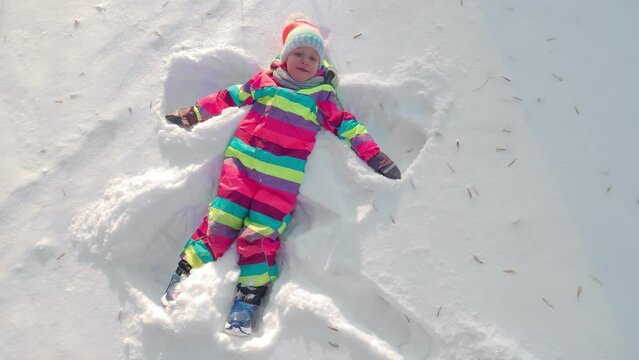 Kid having winter fun and making snow angel