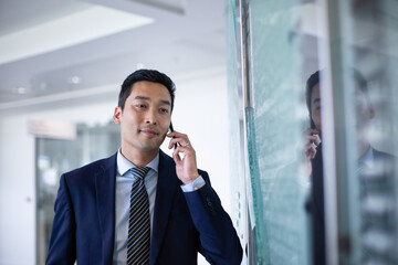 Asian businessman looking at reflection in a modern corporate office