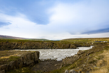 Flow of the river toward a bridge through Icelandic landscape