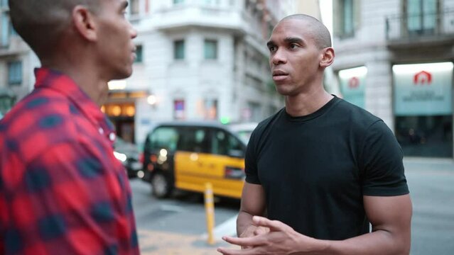 Two serious bald African brothers talking on the street outdoors 