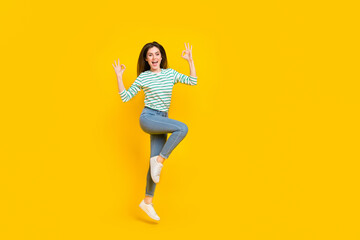 Fototapeta na wymiar Full size photo of good mood overjoyed girl jumping showing okay symbol isolated on yellow color background