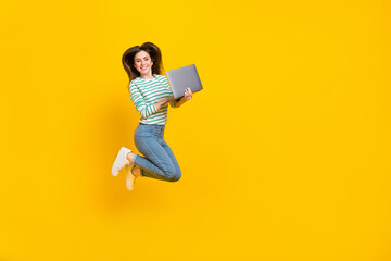 Full size photo of adorable business lady working remotely on new project jumping up isolated on yellow color background