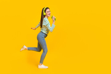 Fototapeta na wymiar Full body profile side photo of laughing cheerful girl listen music in headset use phone as mic isolated on yellow color background
