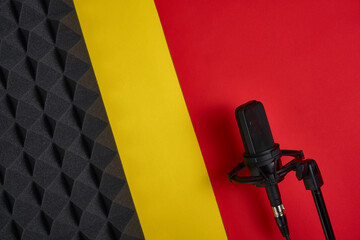 Microphone on red and yellow background with copy space and acoustic foam panel