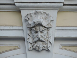Stone head of men decorative element on the facade of the building