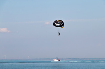 tourists hover above the water with a parachute tied to a boat