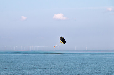 tourists hover above the water with a parachute tied to a boat