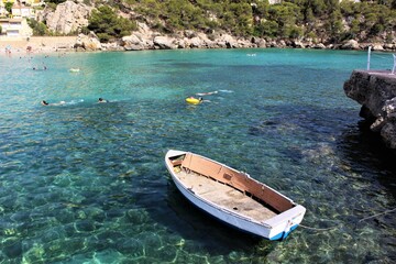 Naklejka na ściany i meble Lonely boat floating on crystal clear water. Mallorca, Spain. 
