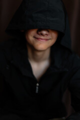 Portrait of blonde teenage boy on dark background outdoor. Low key close up shot of a young teen boy, adolescence. Selective focus. Loneliness, emotional, joy, happiness