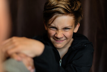 Portrait of blonde teenage boy on dark background outdoor. Low key close up shot of a young teen boy, adolescence. Selective focus. Loneliness, emotional, joy, happiness