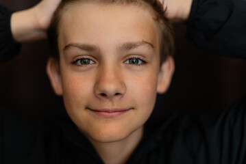 Portrait of blonde teenage boy on dark background outdoor. Low key close up shot of a young teen boy, adolescence. Selective focus. Loneliness, emotional, joy, happiness