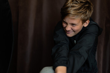 Portrait of blonde teenage boy on dark background outdoor. Low key close up shot of a young teen boy, adolescence. Selective focus. Loneliness, emotional, joy, happiness