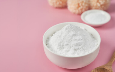 concept of collagen powder in a wood bowl and spoon on pink table background. protein intake. flower and plant. collagen, collagen powder, fiber                         