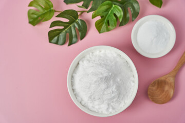 Fototapeta na wymiar concept of collagen powder in a wood bowl and spoon on pink table background. protein intake. flower and plant. top view flat lay. collagen, collagen powder, fiber 