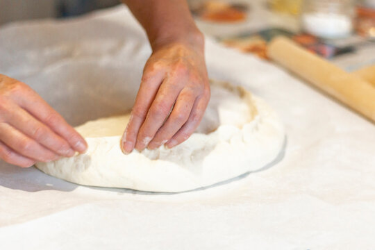 Women's hands sculpt from the dough a large pirok with potatoes and msyaom. Home national cuisine