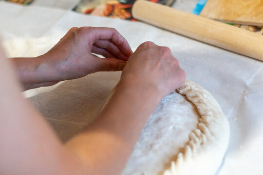 Women's hands sculpt from the dough a large pirok with potatoes and msyaom. Home national cuisine