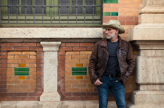 Portrait of adult man in cowboy hat against building