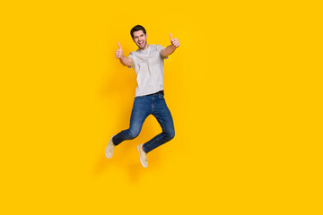 Fototapeta na wymiar Full length body size view of attractive cheerful guy jumping giving two thumbup isolated over bright yellow color background