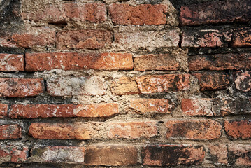 Old red brick stone wall exterior on ancient temple architecture in Ayutthaya, Thailand.