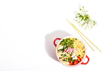 Asian noodles with chicken, vegetables, and herbs are isolated on a white background