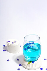 Cold tonic water and blue forget me not flowers on stand isolated on a white background