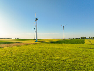 Aerial drone view of wind power turbines, part of a wind farm. Wind turbines on green field in countryside. Wind power plant.