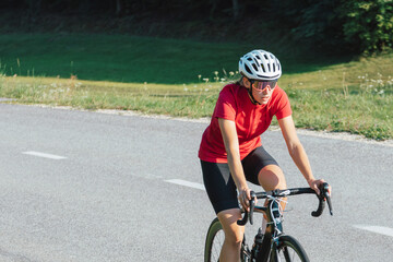 Young female professional bicyclist during road cycling sprint, continual motion with maximal effort, close-up view.