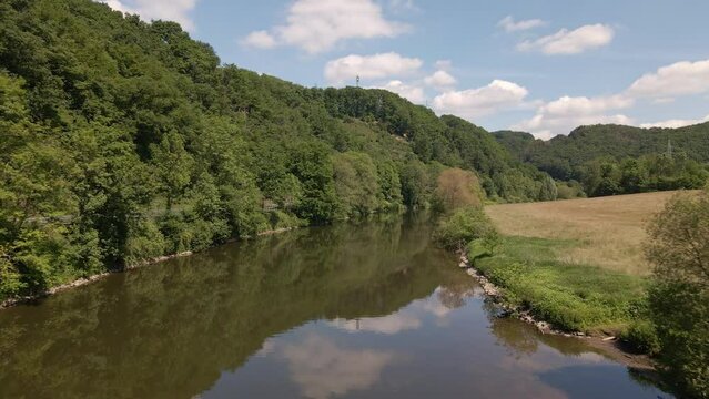 The calm Sieg river in Schladern, Germany on a beautiful sunny morning. Slow aerial fly over