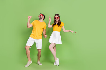 Full body photo of two overjoyed carefree people have fun dancing clubbing isolated on green color...